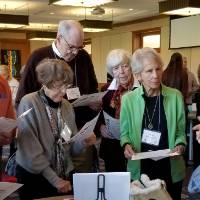 A young woman is speaking to a group of older people